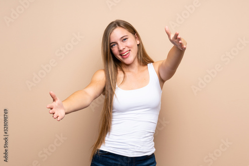 Teenager blonde girl over isolated background presenting and inviting to come with hand