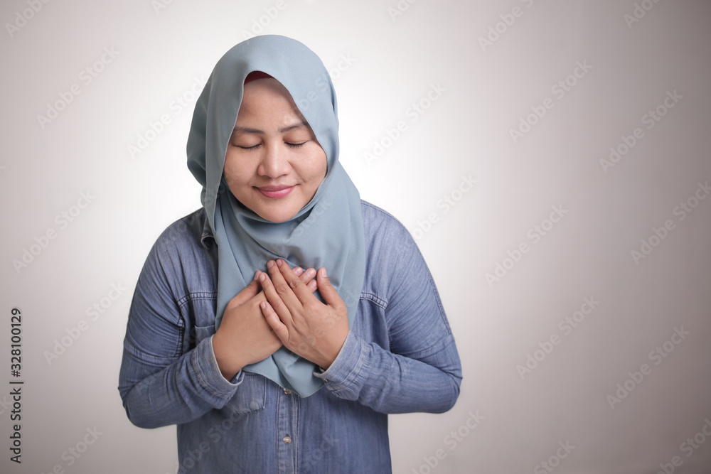 Muslim Woman Close Her Eyes, Hands on Heart and Pray Muslim Woman Close Her Eyes, Hands on Heart and Pray