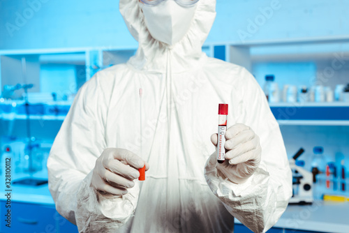 Tablou pe pânză cropped view of scientist in latex gloves and medial mask holding test tube with