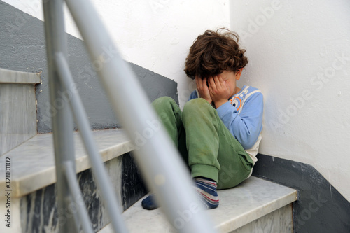 Little European Caucasian children crying sitting on the ground after being punished by parents - violence against minors photo