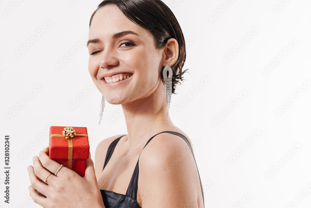 Image of young happy woman smiling and holding small present box Image of young happy woman smiling and holding small present box