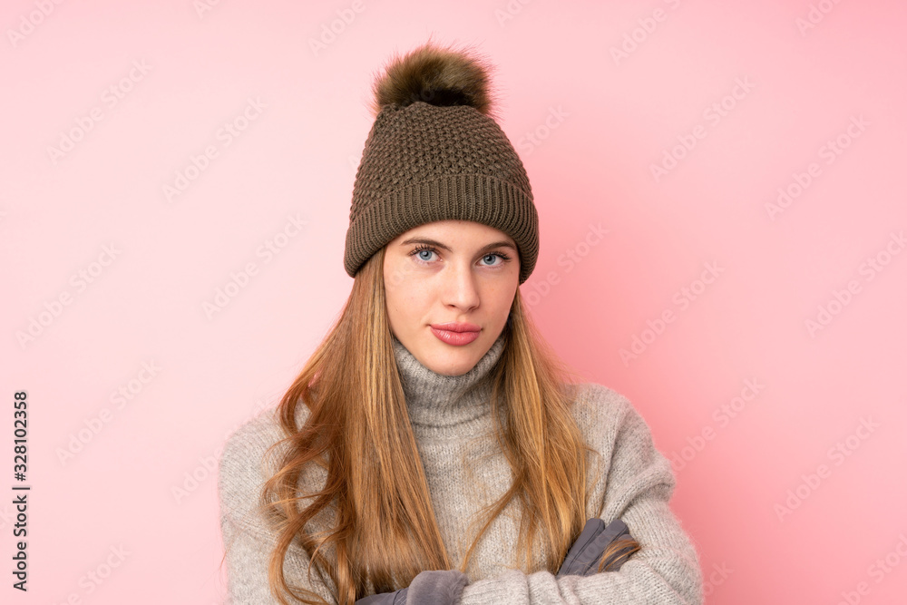 Young teenager girl with winter hat over isolated pink background keeping arms crossed Young teenager girl with winter hat over isolated pink background keeping arms crossed
