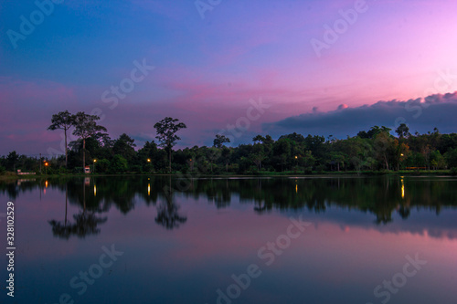 Wallpaper blurred nature of the twilight light in the evening by the large water basin surrounded by big trees,the integrity of the forest