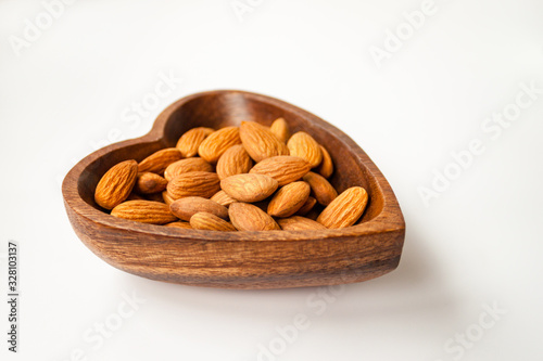 Almond nuts in bamboo wooden bowl on white background isolated