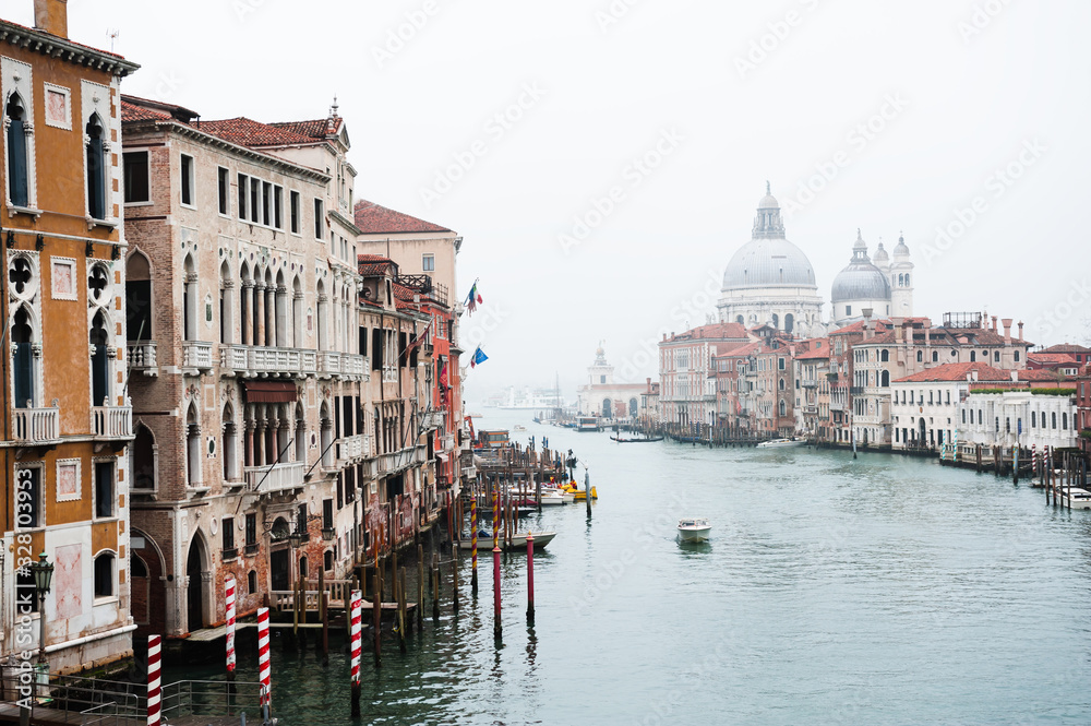 View of Grand Canal and Basilica Santa Maria della Salute in Venice, Italy. Misty overcast day. Famous tourist destination. Travel and vacation concept