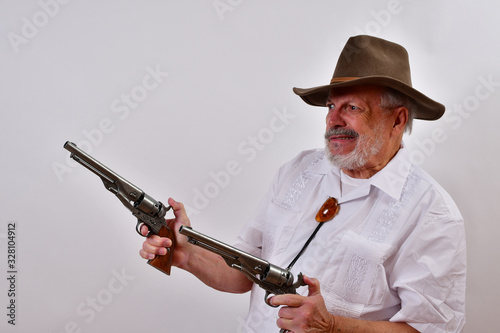 Angry old man aims two revolvers..Elderly gentleman with floppy hat and two revolvers.Senior man looking mean  aiming his pistols .When one gun is not enough.