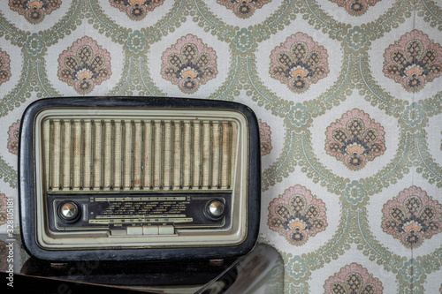 March 1, 2020 - Rome, Italy - Telefunken Mignonette, an old transistor radio, with knobs and buttons for manual tuning. In the background a vintage wallpaper. Ancient object, worn and ruined by time. photo