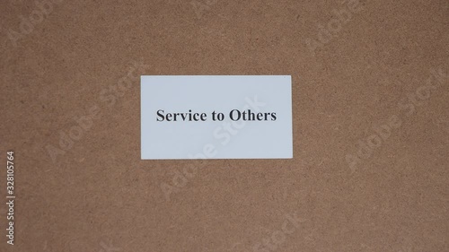 SERVICE TO OTHERS. Top shot - Hand puts paper card with word. CORE VALUE concept