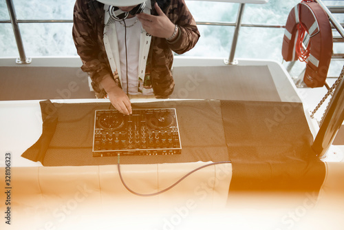 Dj mixes the track playing on the party in yacht. Asian men DJ in the party, DJ remote control, Man spinning turntable,  party in yacht,