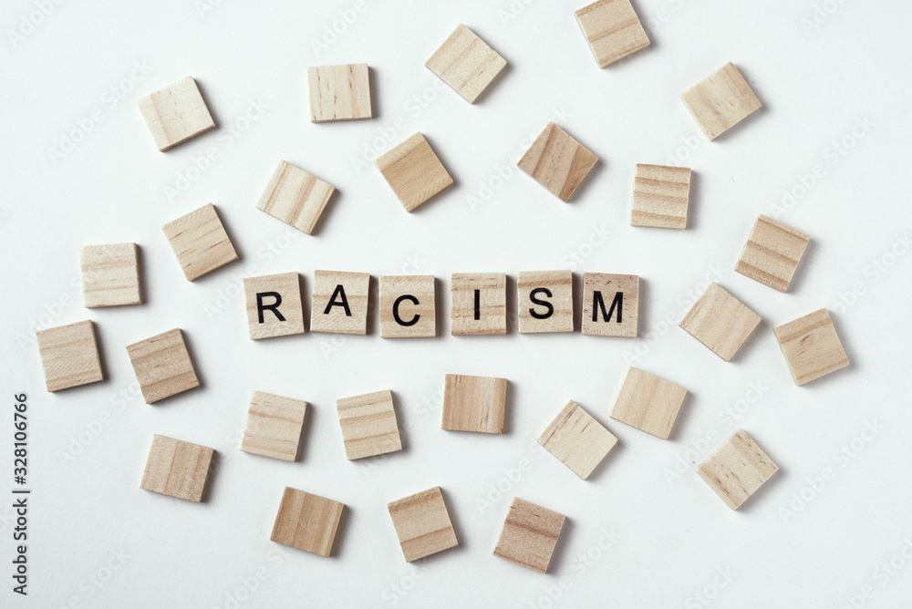 Concept of racism and misunderstanding between people, prejudice and discrimination. Wooden block with word racism on the white backround