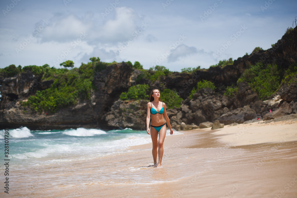 girl in a blue swimsuit walks on a tropical beach girl in a blue swimsuit walks on a tropical beach