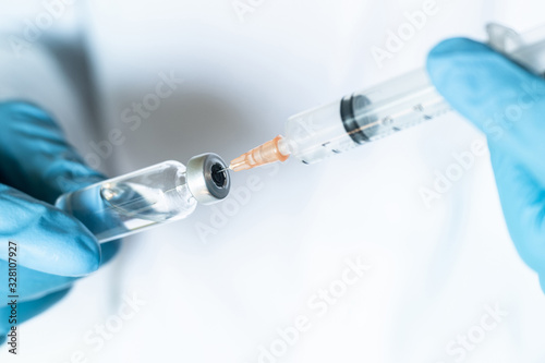 Doctor, nurse or scientist hand in blue nitrile gloves holding flu, measles, coronavirus vaccine shot for baby and adult vaccination, medicine and drug concept