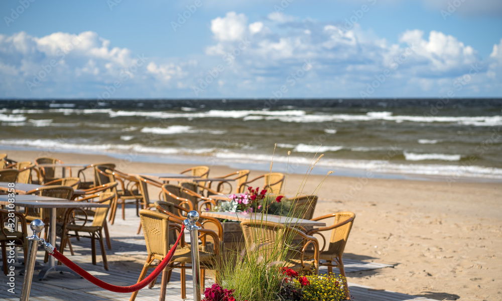 Summer cafe with tables on the sandy Baltic beach in Jurmala in early autumn on a sunny windy day. Latvia
