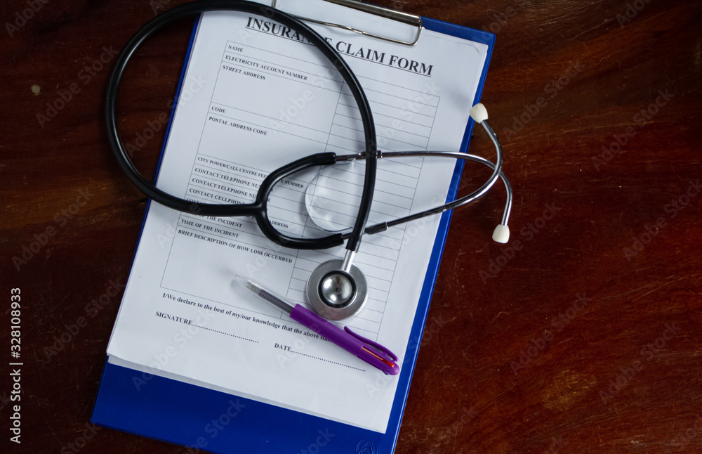 The stethoscope and Insurance claim form put on wooden desk The stethoscope and Insurance claim form put on wooden desk