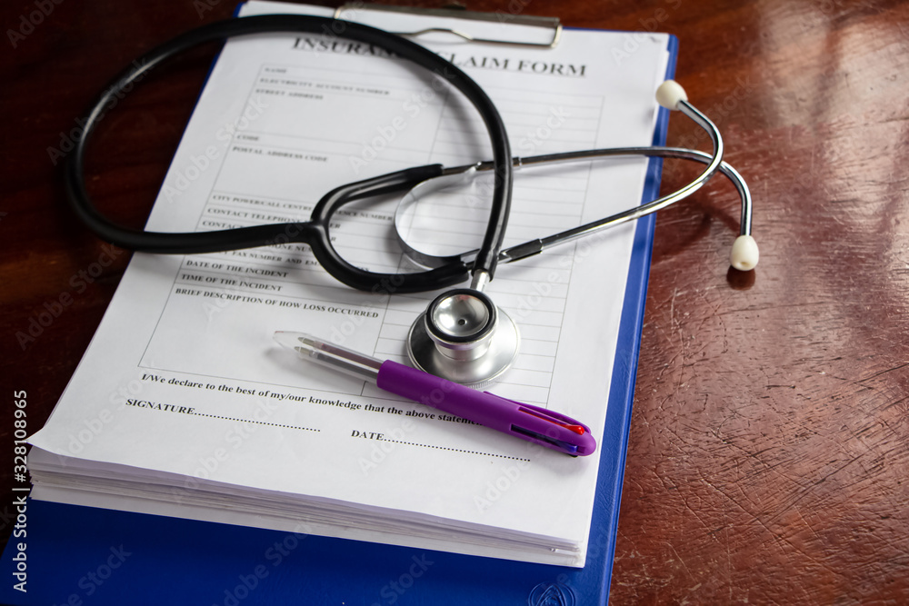 The stethoscope and Insurance claim form put on wooden desk