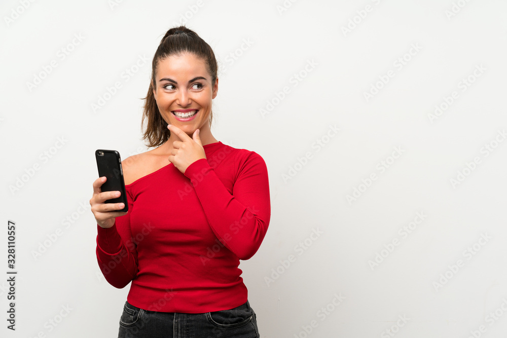Young woman using mobile phone thinking an idea and looking side Young woman using mobile phone thinking an idea and looking side