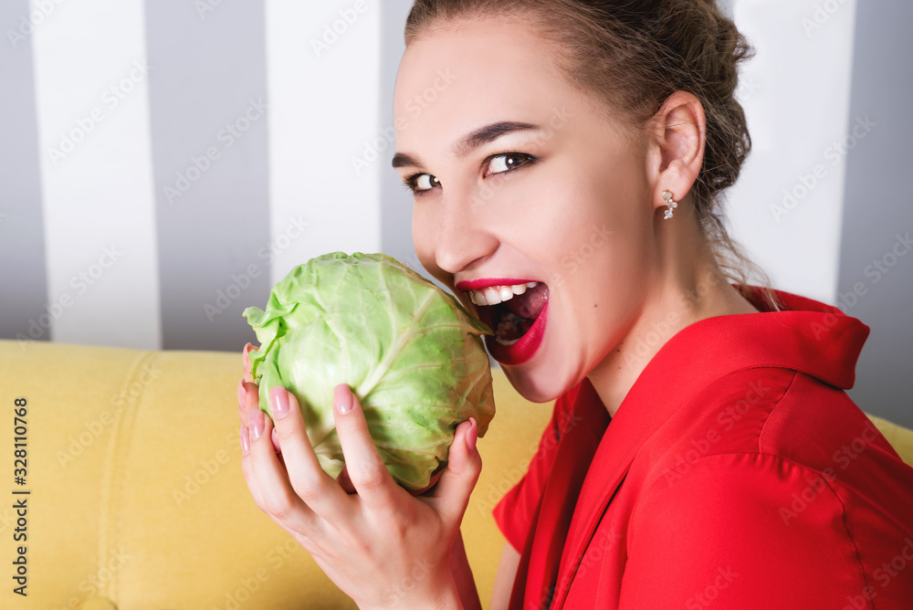A beautiful girl holds cabbage in her hands, pretending to eat it A beautiful girl holds cabbage in her hands, pretending to eat it