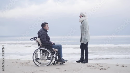 Wallpaper Mural Cheerful Caucasian woman talking with boy in wheelchair and pointing away. Adult mother and young disabled son spending autumn day on sea shore outdoors. Leisure, lifestyle, rehabilitation. Torontodigital.ca