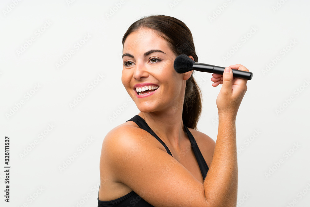 Young woman over isolated white background with makeup brush Young woman over isolated white background with makeup brush