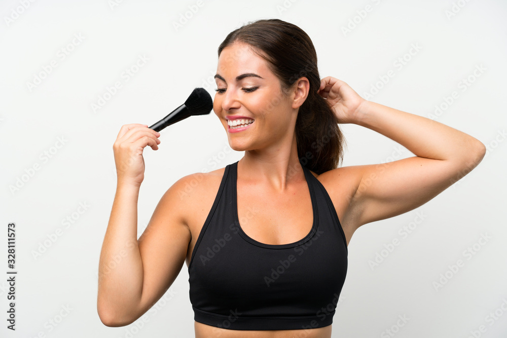 Young woman over isolated white background with makeup brush Young woman over isolated white background with makeup brush