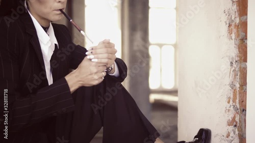 portrait adult smoking woman holding cigarette holder brunette with long hair in suit and white shirt sitting in abandoned building