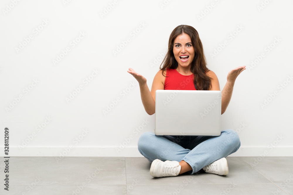 Young woman with a laptop sitting on the floor unhappy and frustrated with something Young woman with a laptop sitting on the floor unhappy and frustrated with something