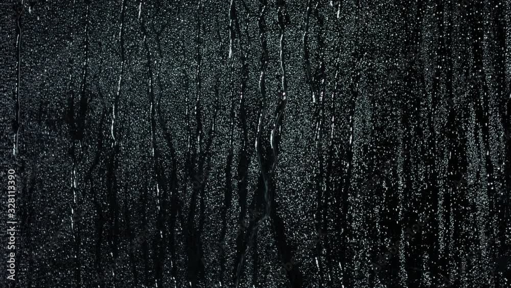 Glass with rain drops against dark background