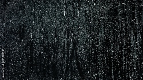Glass with rain drops against dark background
