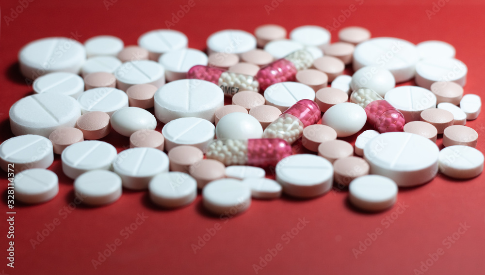 Heap of white pills, tablets, capsules on red background. Drug prescription for treatment medication health care concept wth copy space. Heap of white pills, tablets, capsules on red background. Drug prescription for treatment medication health care concept wth copy space.