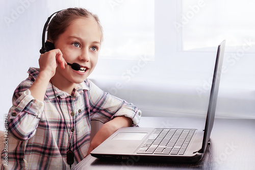 Teenage girl with headset goes onlinetraining for a computer at home photo