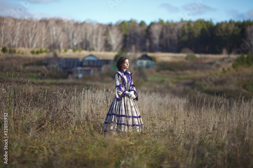 beautiful girl in a suit of the 19th century walks in the village