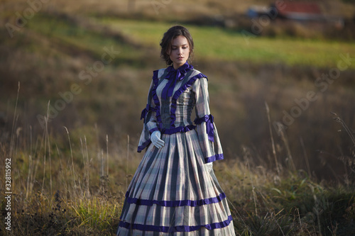 beautiful girl in a suit of the 19th century walks in the village