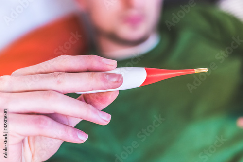 Flu and corona concept: Man is holding a fever thermometer in his hand, close up