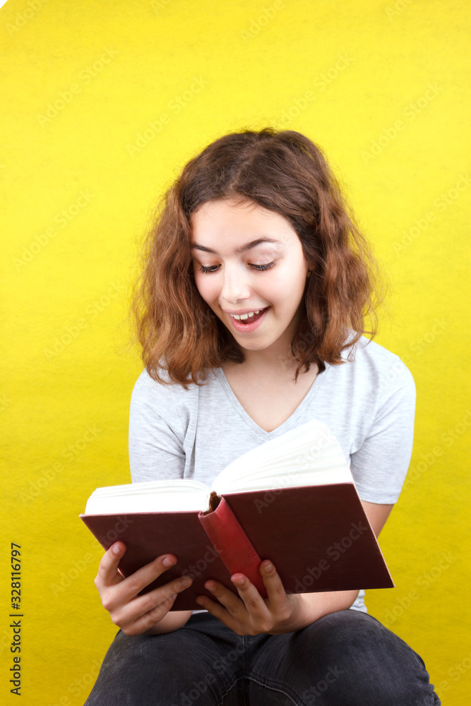 Curly beautiful girl reads a funny book and laughs Curly beautiful girl reads a funny book and laughs