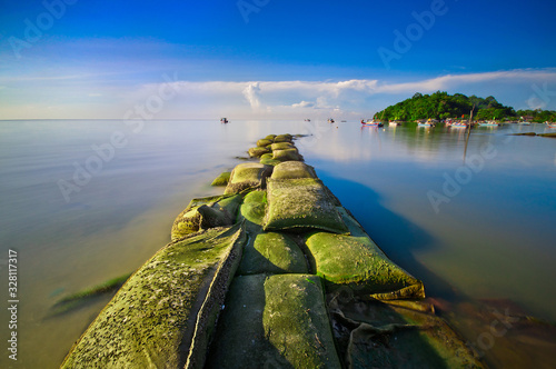 Wave breaker at Gertak Sanggul, Penang. View of fisherman village during beautiful sunny blue sky. photo