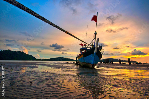 A fisherman boat parking at Tanjung Dawai Beach, Kedah during sunset. photo