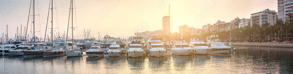 Breathtaking romantic summer panoramic view of boats and yachts in harbor in evening sunshine glow. Costa Blanca. Alicante, province of Valencia, Spain. - obrazy, fototapety, plakaty 