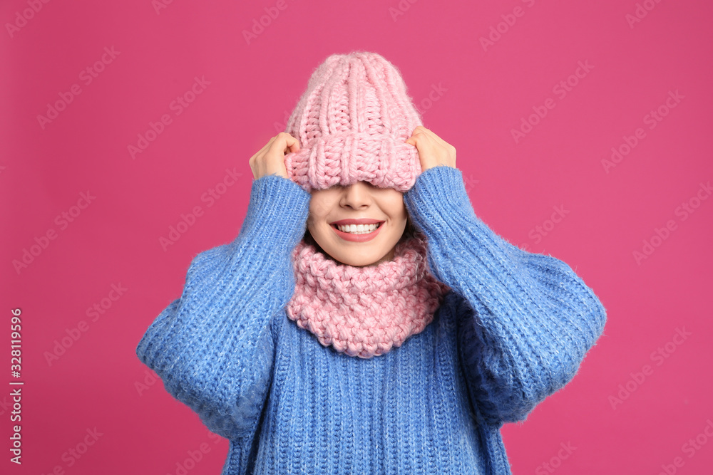 Young woman wearing warm sweater, snood and hat on crimson background. Winter season Young woman wearing warm sweater, snood and hat on crimson background. Winter season