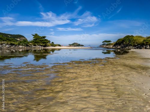 Summer in the lagoon, with beach on the horizon, blue sky, clouds reflected in calm water, holiday, holidays or weekend pleasures, walking to the sea during low tide.