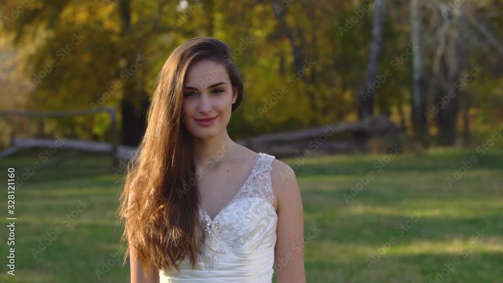 Beautiful brunette bride with deep look is looking right and begins to smiling in sunny rays at the autumn park. Beautiful brunette bride with deep look is looking right and begins to smiling in sunny rays at the autumn park.