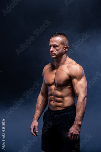 Muscular man isolated on the black background. Strong male naked torso abs