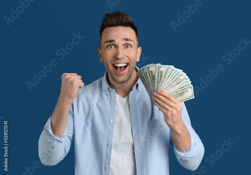 Emotional man with cash money on blue background