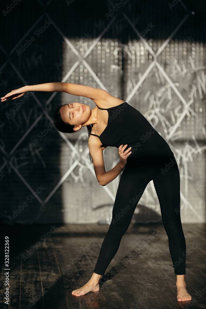 Fototapeta premium Girl is doing stretching exercise. Yoga class in black sportswear.