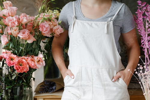 woman in apron standing on flower background. Entrepreneurship, florist, craftsman, artisan, craft, service, cook,  small business, workplace concept