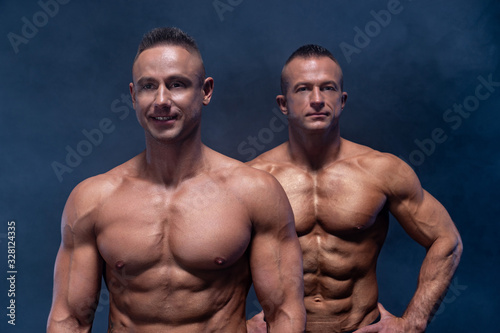 Two Muscular man isolated on the black background. Strong male naked torso abs