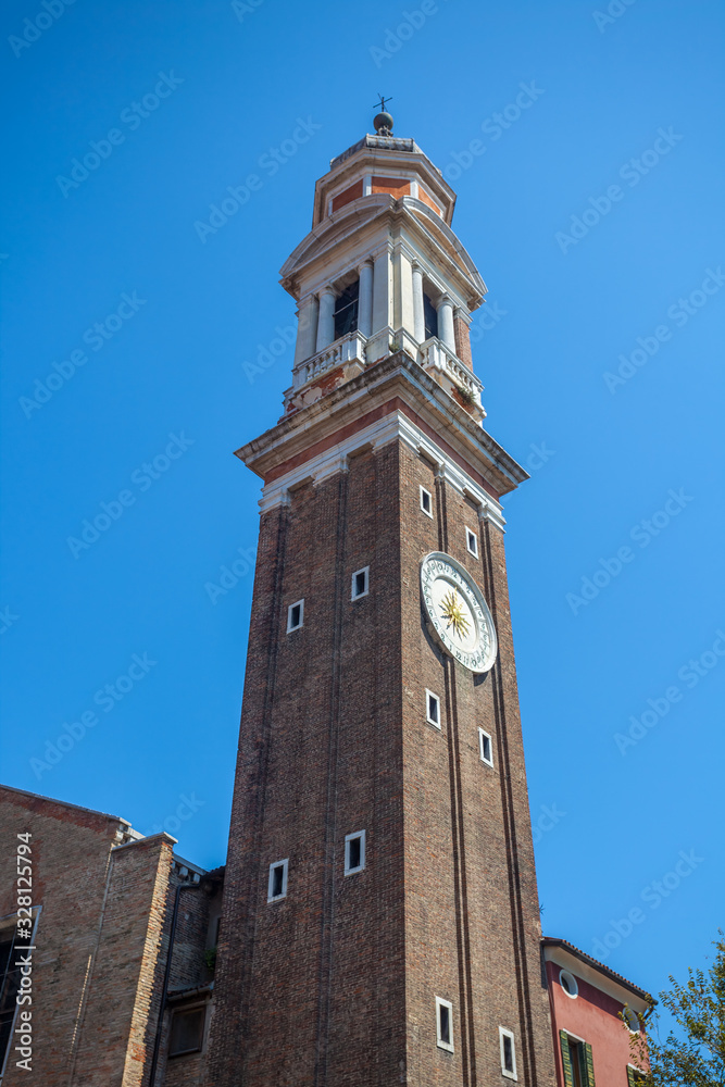 The tower Of the Church of Santi Apostoli in Venice against the blue sky