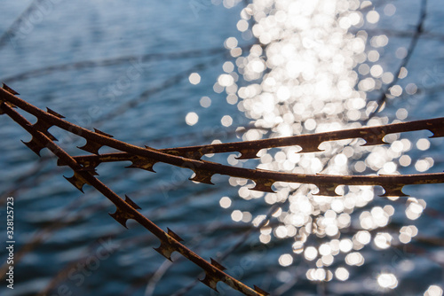 Φωτογραφία Rusty nato wire, rusty barbed wire, water in the background, border, abstract