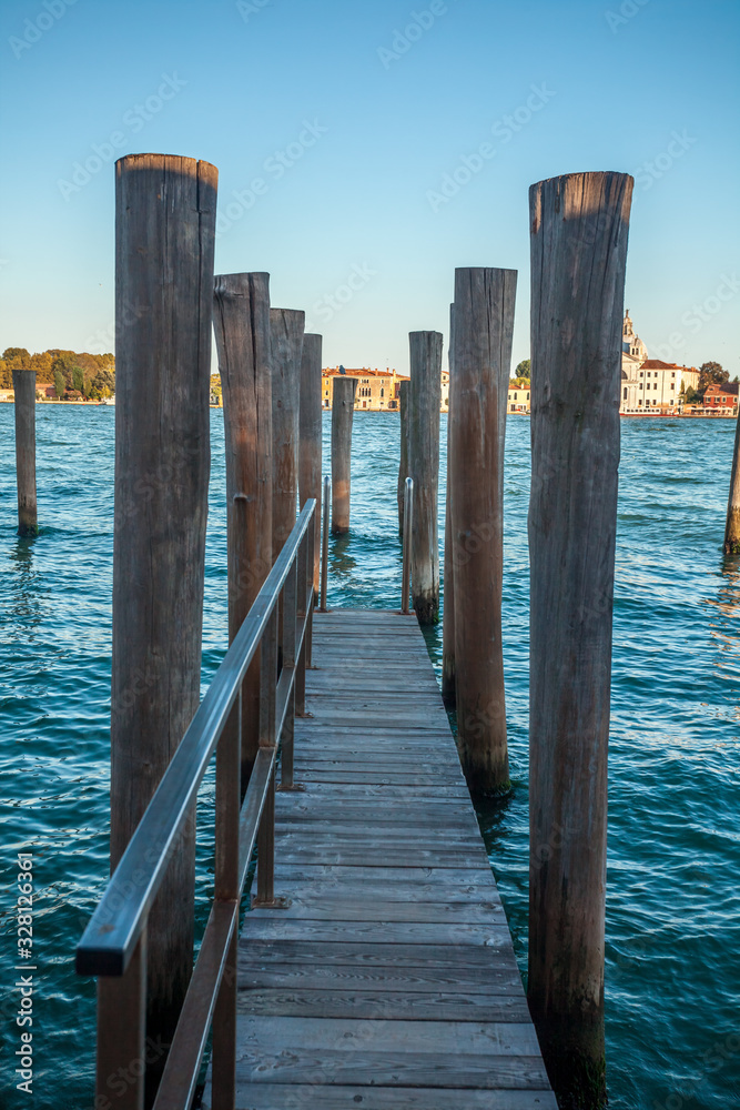 Pier wooden poles tightened together by rusty chains on canal in Venice Pier wooden poles tightened together by rusty chains on canal in Venice