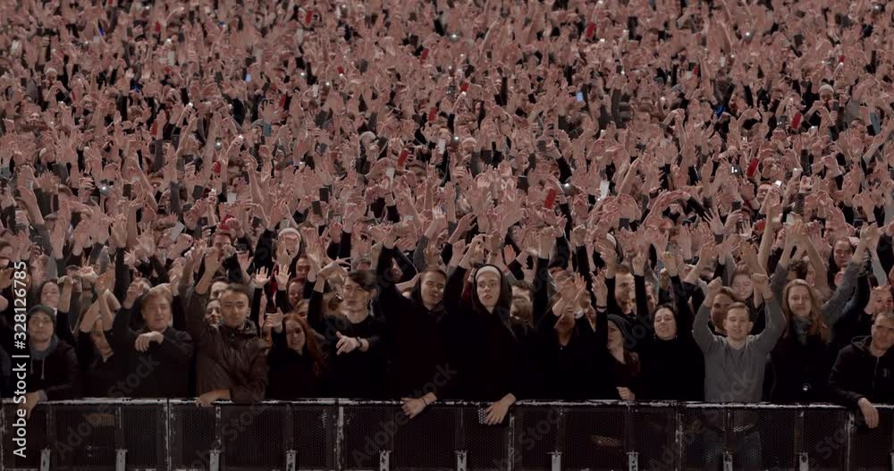 Model released, Front view of huge crowd dancing and cheering at a concert or a show behind control barrier. Shot on RED Helium 8K Prores 4444