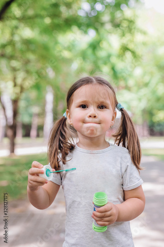 Cute little girl with a soap bubbles in park